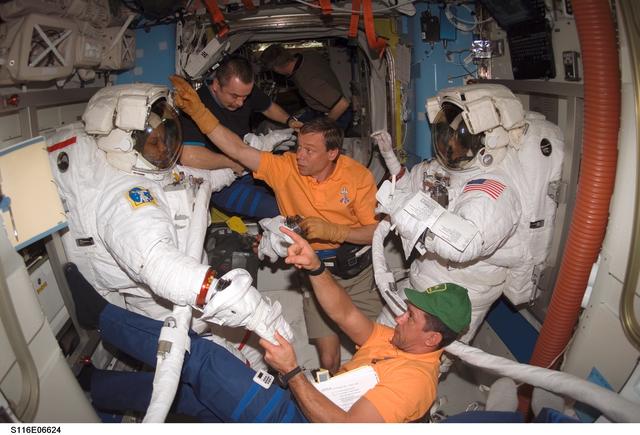 NASA image: STS-116 Crewmembers Curbeam and Williams are removing their EMUs after spacewalk