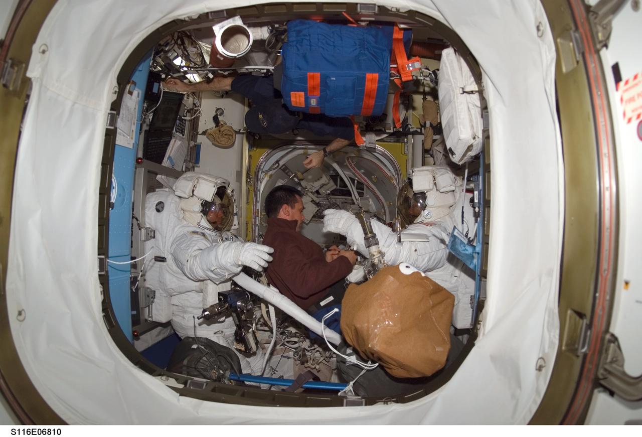 S116-E-06810 (18 Dec. 2006) --- Attired in their extravehicular mobility unit (EMU) spacesuits, astronaut Robert L. Curbeam, Jr. (right) and European Space Agency (ESA) astronaut Christer Fuglesang, both STS-116 mission specialists, prepare for the mission's fourth session of extravehicular activity (EVA) in the Quest Airlock of the International Space Station while Space Shuttle Discovery was docked with the station. Astronaut William A. (Bill) Oefelein (center), pilot, assisted Curbeam and Fuglesang.