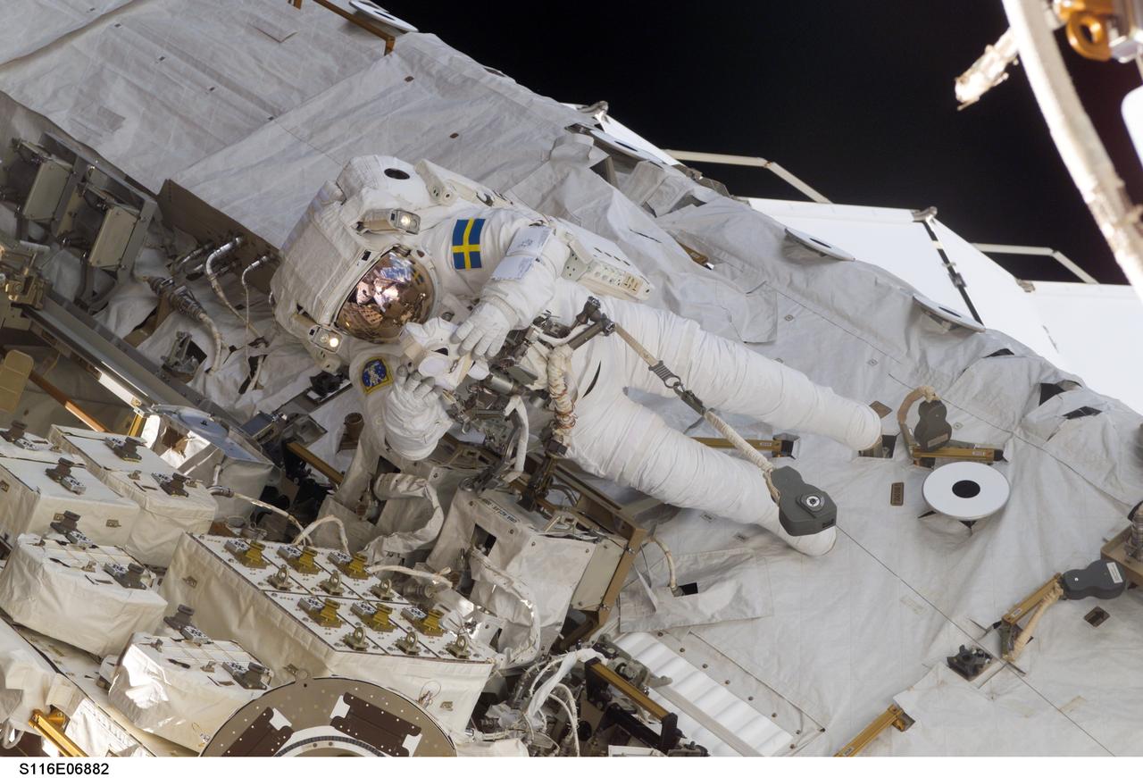S116-E-06882 (18 Dec. 2006) --- European Space Agency (ESA) astronaut Christer Fuglesang, STS-116 mission specialist, uses a digital still camera during the mission's fourth session of extravehicular activity (EVA) while Space Shuttle Discovery was docked with the International Space Station. Astronaut Robert L. Curbeam Jr. (out of frame), mission specialist, worked in tandem with Fuglesang, using specially-prepared, tape-insulated tools, to guide the array wing neatly inside its blanket box during the 6-hour, 38-minute spacewalk.