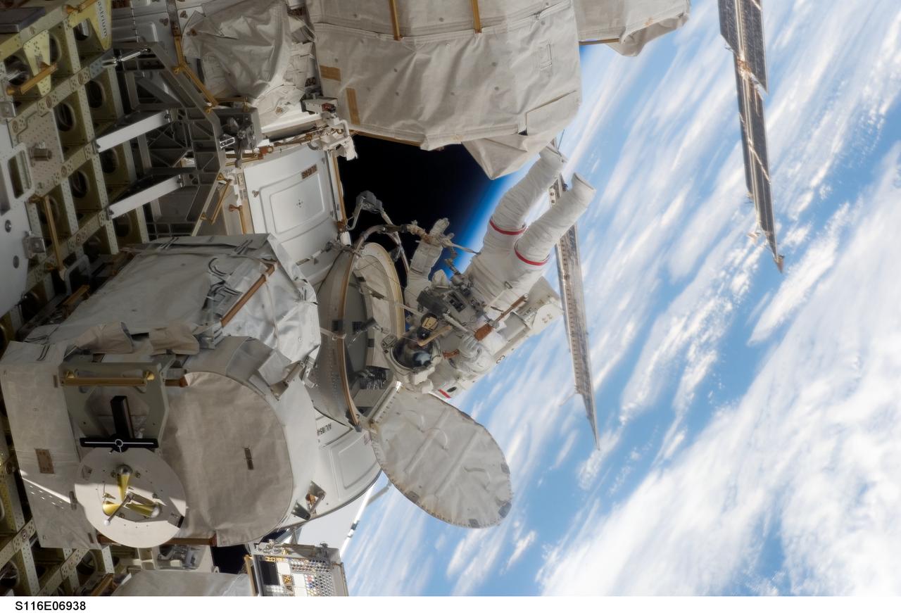 S116-E-06938 (18 Dec. 2006) --- Astronaut Robert L. Curbeam Jr., STS-116 mission specialist, exits the Quest Airlock of the International Space Station as he and European Space Agency (ESA) astronaut Christer Fuglesang (out of frame), mission specialist, begin the mission's fourth session of extravehicular activity (EVA) while Space Shuttle Discovery was docked with the station. Curbeam and Fuglesang worked in tandem, using specially-prepared, tape-insulated tools, to guide the array wing neatly inside its blanket box during the 6-hour, 38-minute spacewalk.