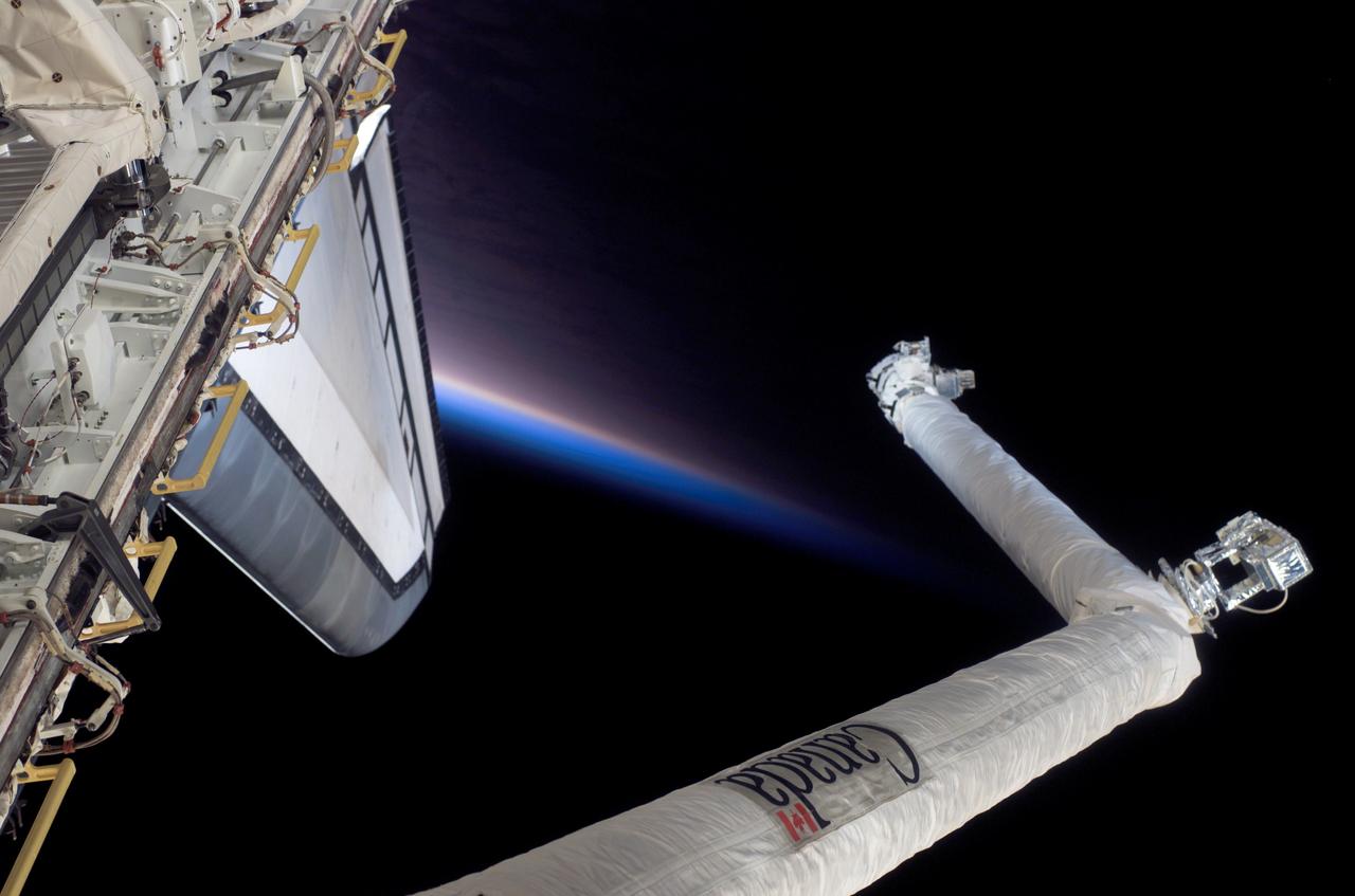 S116-E-07008 (18 Dec. 2006) --- As seen through windows on the aft flight deck of Space Shuttle Discovery, the Remote Manipulator System (RMS) is featured in this image photographed by a STS-116 crewmember during flight day ten activities while Discovery was docked with the International Space Station. The blackness of space, Earth's horizon and airglow provide the backdrop for the scene.