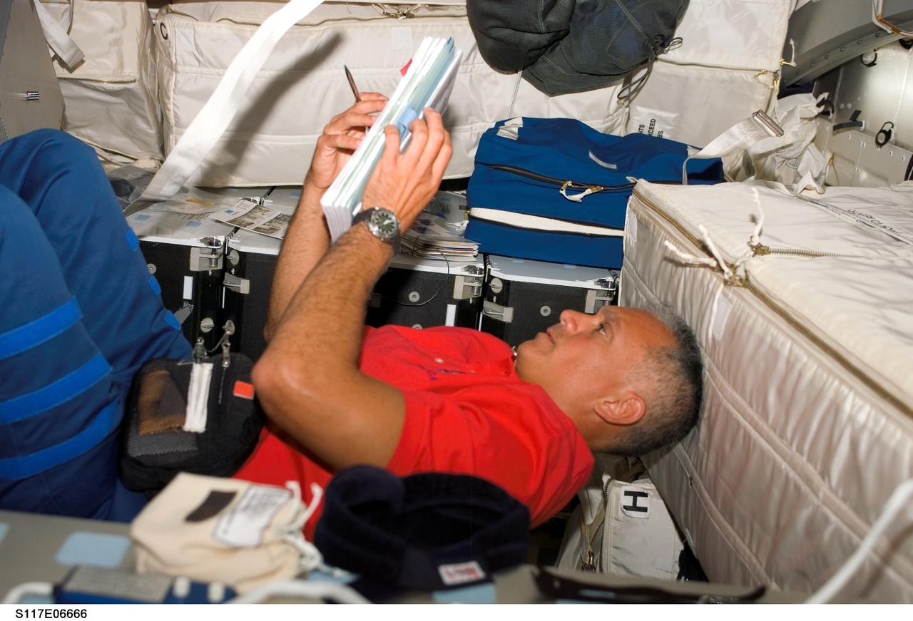 S117-E-06666 (9 June 2007) --- Astronaut John "Danny" Olivas, STS-117 mission specialist, looks over procedures checklists on the middeck of the Space Shuttle Atlantis.
