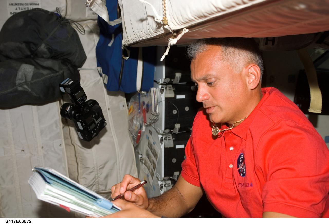 S117-E-06672 (9 June 2007) --- Astronaut John "Danny" Olivas, STS-117 mission specialist, looks over procedures checklists on the middeck of the Space Shuttle Atlantis.