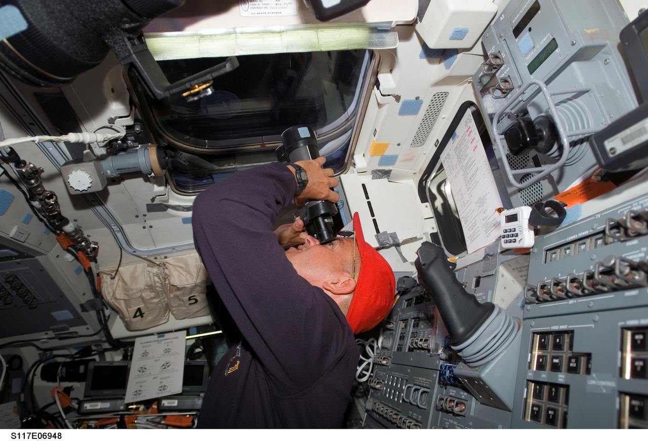 S117-E-06948 (10 June 2007) --- Astronaut Rick Sturckow, STS-117 commander, aims binoculars through one of the overhead windows on the aft flight deck of the Space Shuttle Atlantis as it approaches the International Space Station.