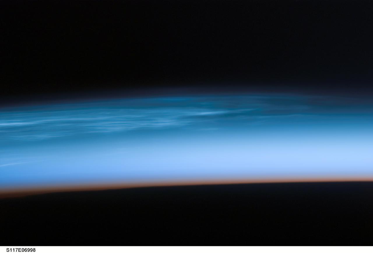 S117-E-06998 (10 June 2007) --- Polar Mesospheric Clouds are featured in this image photographed by a STS-117 crewmember onboard Space Shuttle Atlantis. Sometimes in the summertime in the far northern (or southern) latitudes, high in the Earth's atmosphere at the edge of space, thin silvery clouds form and are observed just after sunset.  These high clouds, occurring at altitudes of about 80 kilometers (50 miles), are called Polar Mesospheric Clouds (PMC) or noctilucent clouds, and are the subject of new studies to determine whether their occurrence is related to global climate change. Observations over the past few years suggest that PMC are now observed more frequently and at lower latitudes than historical observations. Several studies related to the International Polar Year (IPY), and the AIM (Aeronomy of Ice in the Mesosphere) spacecraft are underway to collect relevant data on the chemistry and physics of the mesosphere that might explain the occurrence of PMC.  Astronauts in orbiting spacecraft frequently observe PMC over Canada, northern Europe and Asia during June, July and August. While PMC also occur over the high latitudes in the southern hemisphere in December, January and February, astronaut observations of southern PMC are less frequent.  Earlier in June 2007, the shuttle crew visiting the International Space Station observed spectacular PMC over north-central Asia. This image was taken looking north while the shuttle and station were docking and flying over the border between western China, Mongolia and Kazakhstan. The red-to-dark region at the bottom of the image is the dense part of the Earth's atmosphere. Because this image was taken with a long lens (180mm), the entire profile of the Earth's limb is not captured. To support IPY research over the next 2 years, station crewmembers will be looking for and documenting PMC in both hemispheres.