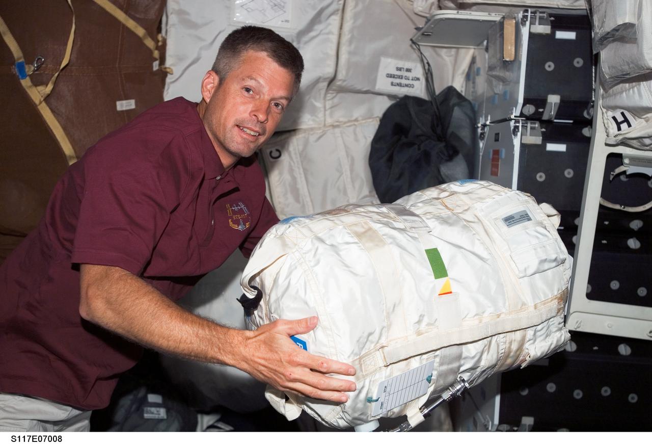 S117-E-07008 (11 June 2007) --- Astronaut Steven Swanson, STS-117 mission specialist, moves a stowage bag on the middeck of the Space Shuttle Atlantis while docked with the International Space Station.