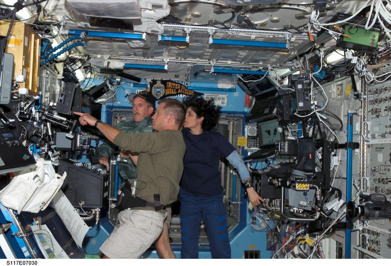 S117-E-07030 (12 June 2007) --- Astronauts Steven Swanson (foreground), Jim Reilly (left) and Sunita L. Williams, all STS-117 mission specialists, work the controls of the Space Station Remote Manipulator System (SSRMS) or Canadarm2 in the Destiny laboratory of the International Space Station while Space Shuttle Atlantis was docked with the station.
