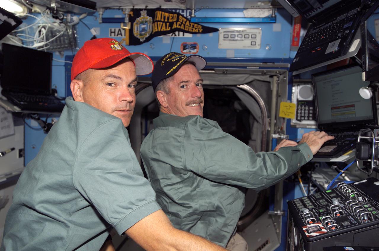 S117-E-07050 (12 June 2007) --- Astronauts Rick Sturckow (left) and Jim Reilly, STS-117 commander and mission specialist, respectively, use a computer in the Destiny laboratory of the International Space Station during flight day five activities while Space Shuttle Atlantis was docked with the station.