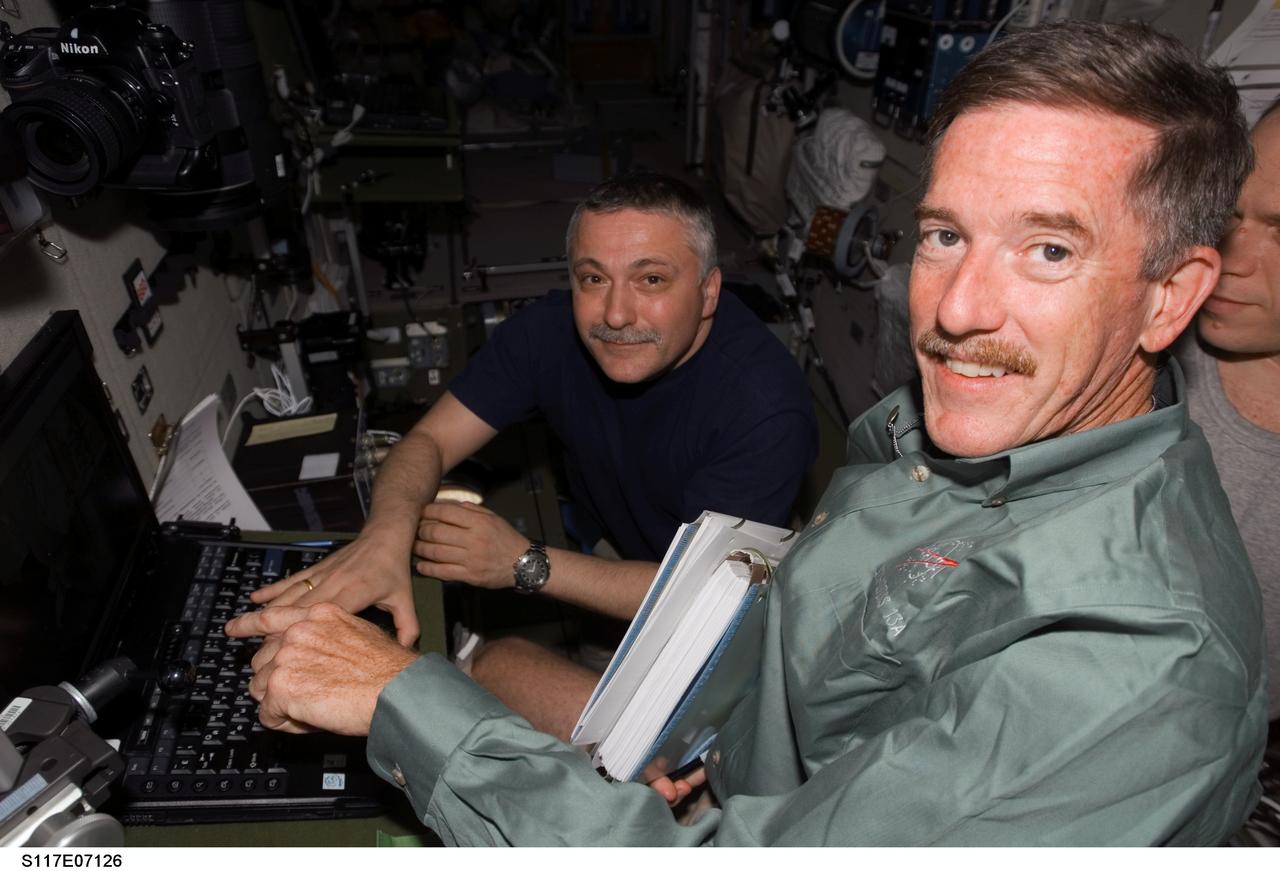S117-E-07126 (12 June 2007) --- Astronaut Jim Reilly (foreground), STS-117 mission specialist; cosmonauts Fyodor N. Yurchikhin (left) and Oleg V. Kotov (right, partially out of frame), Expedition 15 commander and flight engineer, respectively, representing Russia's Federal Space Agency, work tasks in the Zvezda Service Module of the International Space Station while Space Shuttle Atlantis was docked with the station.