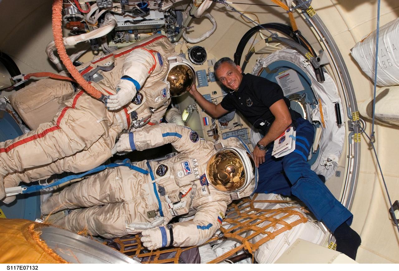 S117-E-07132 (12 June 2007) --- Astronaut John "Danny" Olivas, STS-117 mission specialist, poses with two Russian Orlan spacesuits in the Pirs Docking Compartment of the International Space Station while Space Shuttle Atlantis was docked with the station.