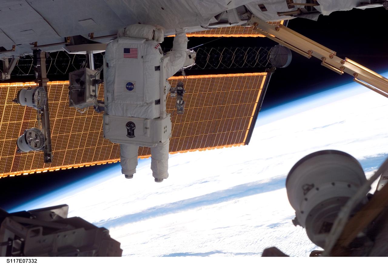 S117-E-07332 (13 June 2007) --- Astronauts Steven Swanson and Patrick Forrester (out of frame), both STS-117 mission specialists, participate in the mission's second planned session of extravehicular activity (EVA), as construction resumes on the International Space Station. Among other tasks, Forrester and Swanson removed all of the launch locks holding the 10-foot-wide solar alpha rotary joint in place and began the solar array retraction.