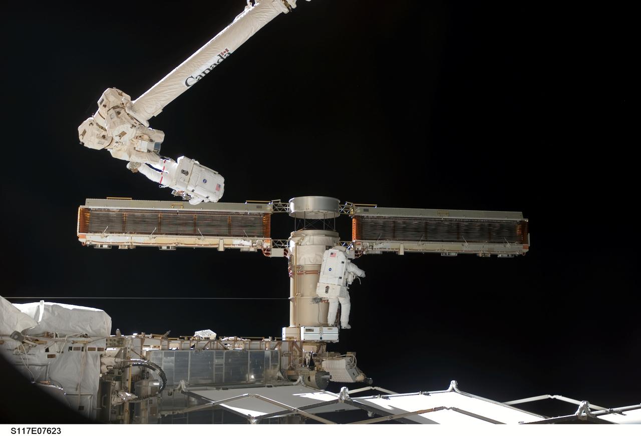 S117-E-07623 (15 June 2007) --- Astronauts Jim Reilly (on robot arm) and John "Danny' Olivas  join up forces with their colleagues inside the shuttle and station and flight controllers in Houston to complete the delicate process of folding an older solar array so that it can be moved from its temporary location to its permanent home during a shuttle mission this fall. This was part of the 7-hour, 58-minute spacewalk by the two mission specialists, who successfully worked through a very busy agenda.