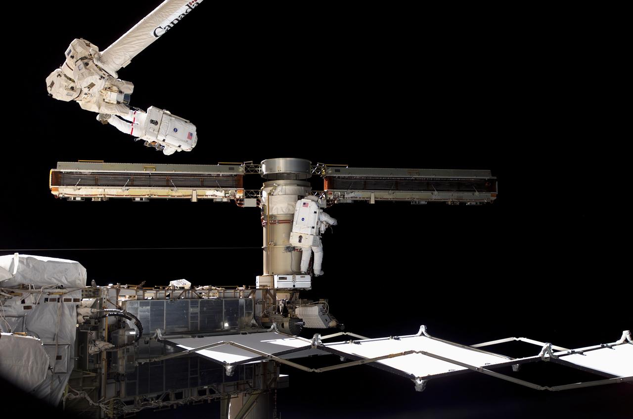 S117-E-07625 (15 June 2007) --- Astronauts Jim Reilly (on robot arm) and John "Danny' Olivas join up forces with their colleagues inside the shuttle and station and flight controllers in Houston to complete the delicate process of folding an older solar array so that it can be moved from its temporary location to its permanent home during a shuttle mission this fall. This was part of the 7-hour, 58-minute spacewalk by the two mission specialists, who successfully worked through a very busy agenda.