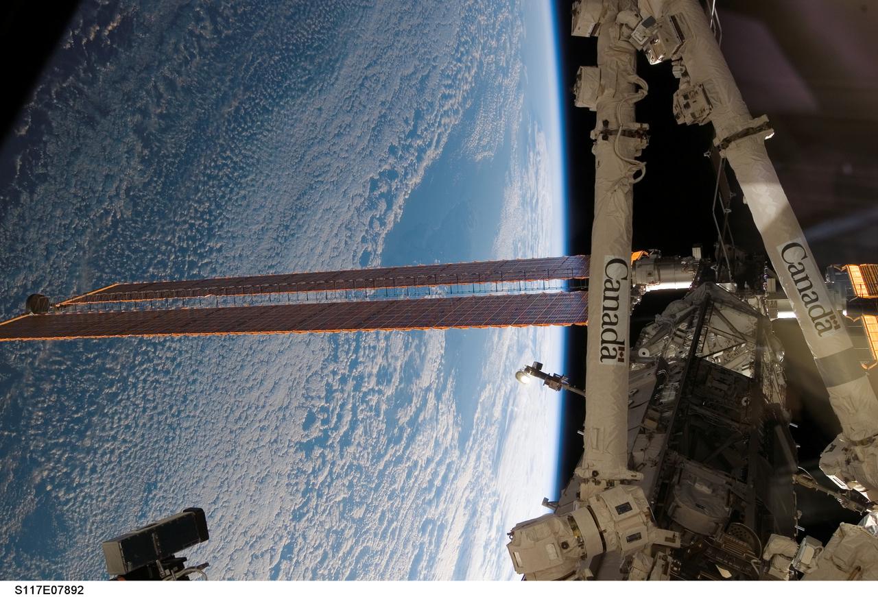 S117-E-07892 (18 June 2007) --- The International Space Station's Canadarm2, or Space Station Remote Manipulator System (SSRMS) and solar array wings are featured in this image photographed by a crewmember on the station while Space Shuttle Atlantis was docked with the orbital complex. The blackness of space and Earth's horizon provides the backdrop for the scene.