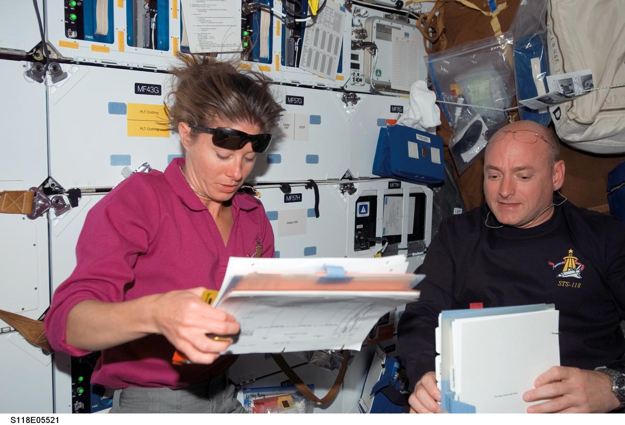 S118-E-05521 (9 Aug. 2007) --- Astronauts Scott Kelly (right), STS-118 commander, and Tracy Caldwell, mission specialist, look over procedures checklists on the middeck of Space Shuttle Endeavour during flight day two activities.