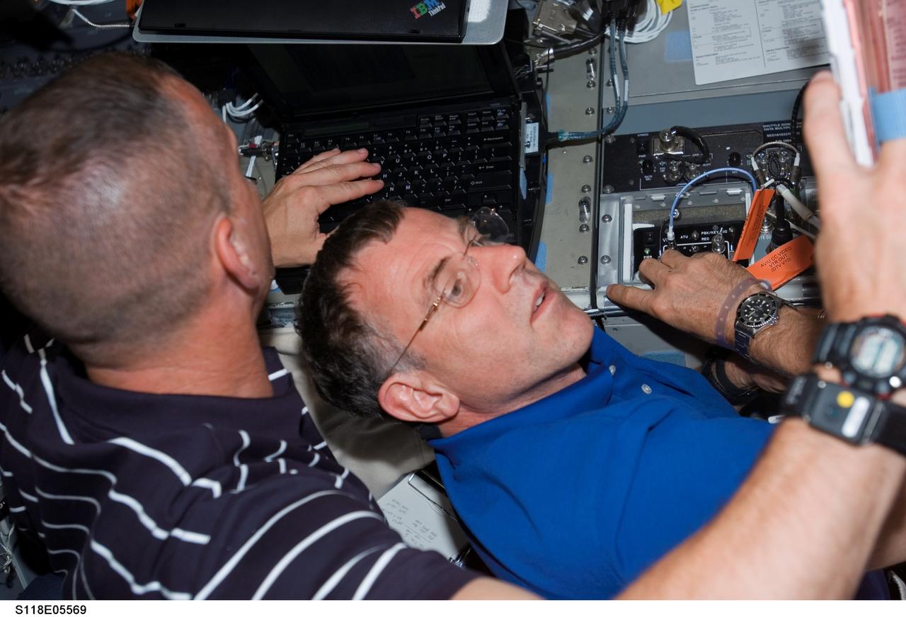 S118-E-05569 (9 Aug. 2007) --- Astronauts Charlie Hobaugh (left), STS-118 pilot, and Dave Williams, mission specialist representing the Canadian Space Agency, work various tasks on the flight deck of Space Shuttle Endeavour during flight day two activities.