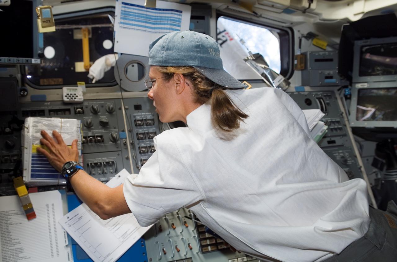 S118-E-06142 (11 Aug. 2007) --- Astronaut Tracy Caldwell, STS-118 mission specialist, refers to a procedures checklist while working the controls of the shuttle's remote manipulator system (RMS) robotic arm from the aft flight deck of Space Shuttle Endeavour in support of the mission's first planned session of extravehicular activity (EVA) while docked with the International Space Station.