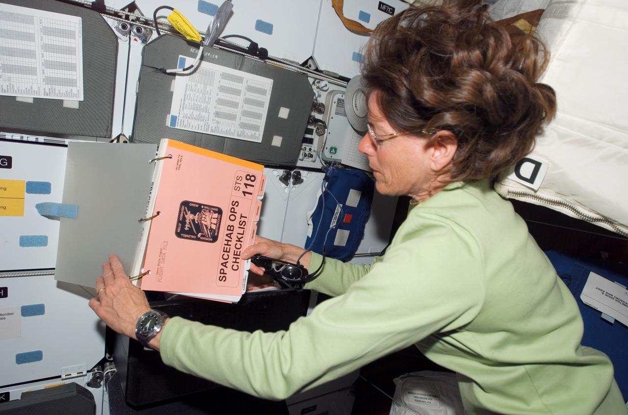 S118-E-06827 (11 Aug. 2007) --- Astronaut Barbara R. Morgan, STS-118 mission specialist, refers to a procedures checklist on the middeck of Space Shuttle Endeavour while docked with the International Space Station during flight day four activities.