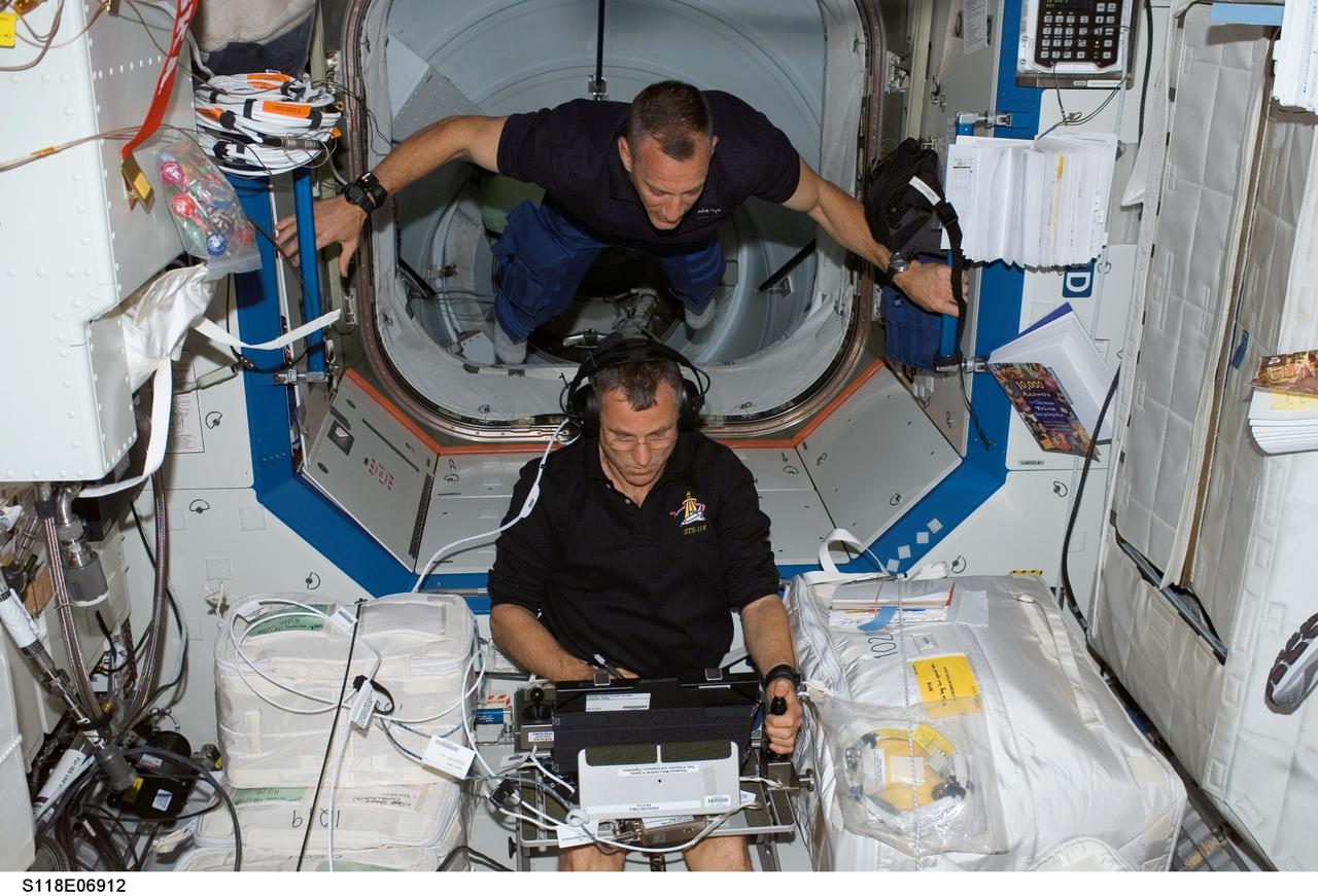 S118-E-06912 (12 Aug. 2007) --- Astronaut Dave Williams, STS-118 mission specialist representing the Canadian Space Agency, works with the Perceptual Motor Deficits in Space (PMDIS) experiment in the Destiny laboratory of the International Space Station. The PMDIS experiment will measure the decline in hand-eye coordination of shuttle astronauts while on orbit. These measurements will be used to evaluate various mechanisms thought to be responsible for the decline. Astronaut Charlie Hobaugh, pilot, looks on as he floats above Williams.