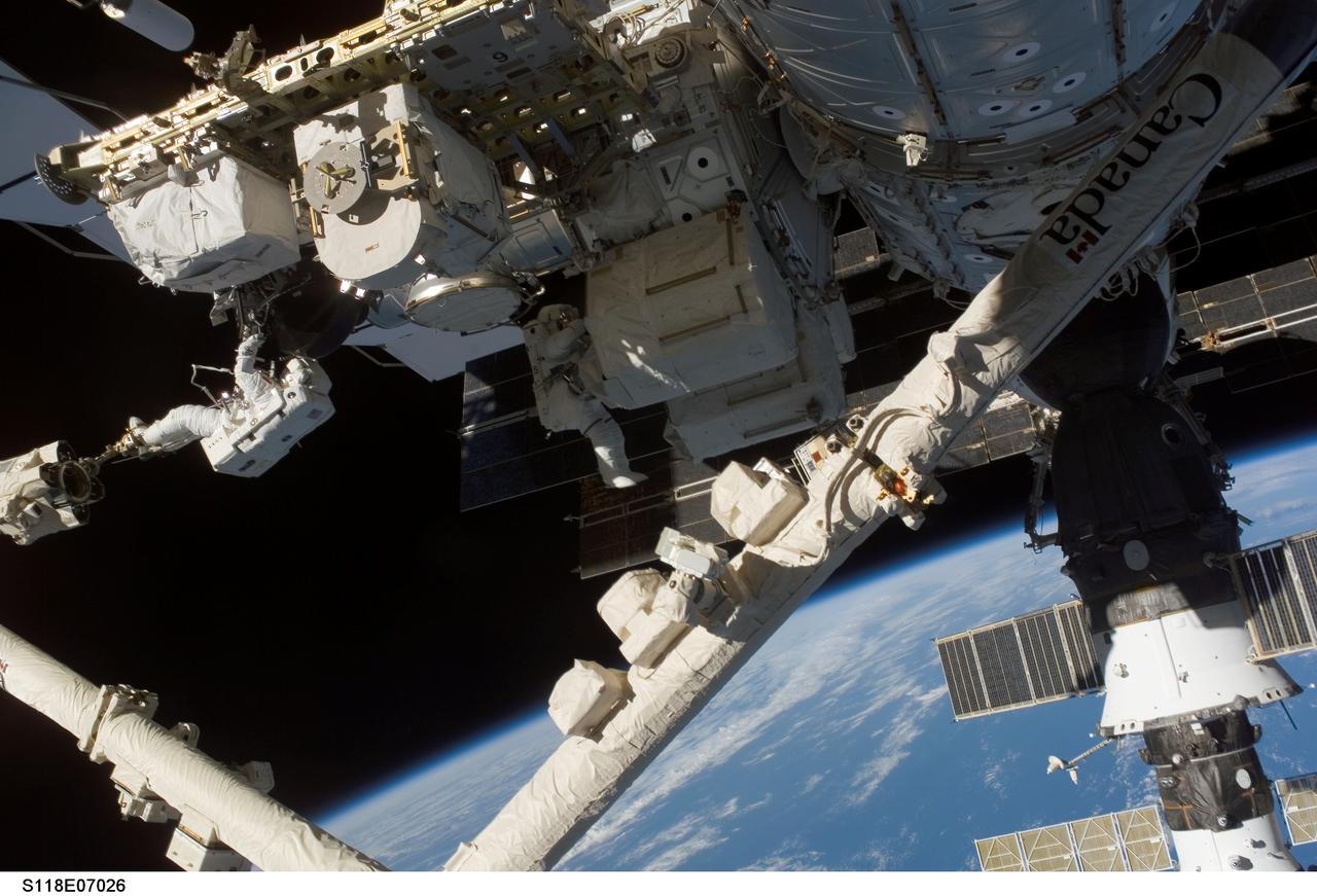 S118-E-07026 (13 Aug. 2007) --- Canadian Space Agency's astronaut Dave Williams (left) and astronaut Rick Mastracchio (center), both STS-118 mission specialists, participate in the mission's second planned session of extravehicular activity (EVA) as construction and maintenance continue on the International Space Station. Williams is anchored to the foot restraint on the stations' Canadarm2. During the 6-hour, 28-minute spacewalk, Williams and Mastracchio removed a faulty control moment gyroscope (CMG-3) and installed a new CMG into the station's Z1 truss. The failed CMG will remain at its temporary stowage location on the station's exterior until it is returned to Earth on a later shuttle mission. The new gyroscope is one of four CMGs that are used to control the station's attitude in orbit.