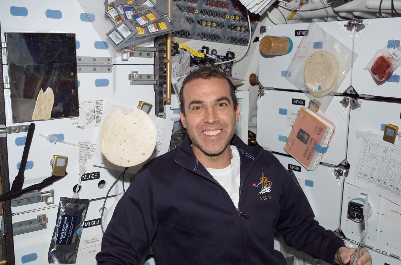 S118-E-07052 (13 Aug. 2007) --- Astronaut Rick Mastracchio, STS-118 mission specialist, smiles for a photo near the galley on the middeck of Space Shuttle Endeavour while docked with the International Space Station. A flour tortilla floats freely near Mastracchio.