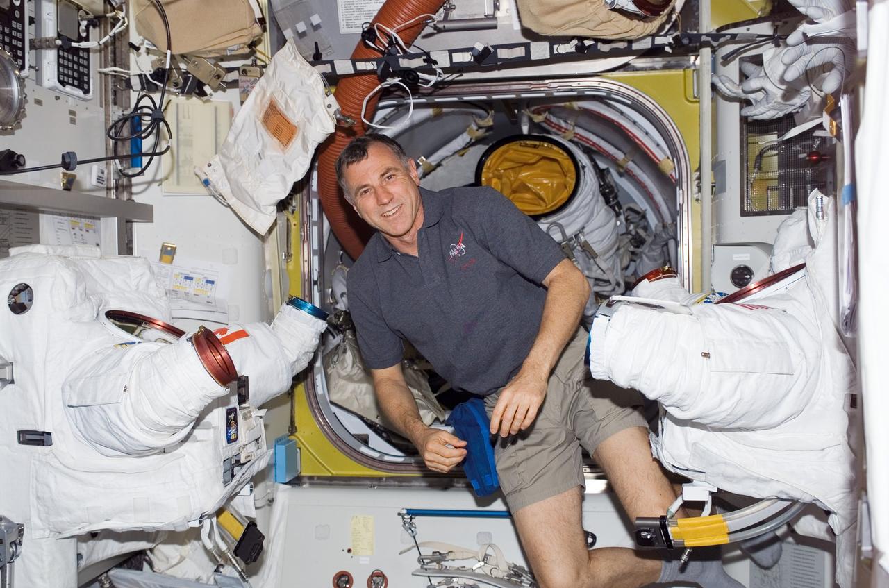 S118-E-07089 (14 Aug. 2007) --- Astronaut Dave Williams, STS-118 mission specialist representing the Canadian Space Agency, floats near torso portions of two extravehicular mobility unit (EMU) spacesuits in the Quest Airlock of the International Space Station while Space Shuttle Endeavour remains docked with the station.