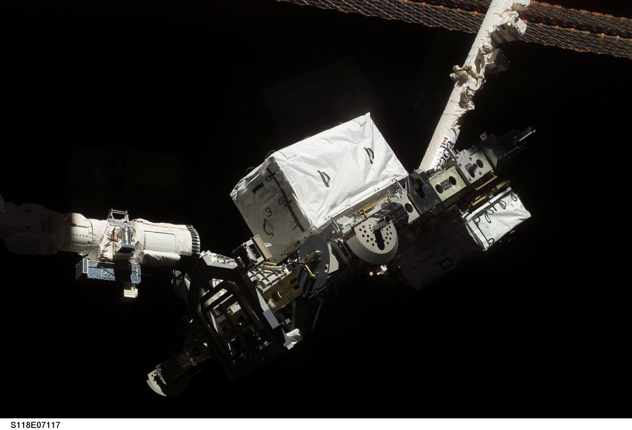 S118-E-07117 (14 Aug. 2007) --- The Space Shuttle Endeavour's Remote Manipulator System (RMS) robotic arm (left) moves away following the hand-off of an external stowage platform (ESP-3) to the station's robotic arm while docked with the International Space Station. Astronauts Tracy Caldwell and Barbara R. Morgan, both STS-118 mission specialists, were inside at Endeavour's controls as the shuttle's robotic arm lifted the storage platform from the cargo bay to hand it over to the station's robotic arm, also known as Canadarm2. Astronauts Charlie Hobaugh, pilot, and Clay Anderson, Expedition 15 flight engineer, then used the Canadarm2 to attach the 13-by-7-foot platform to the station's Port 3 truss.