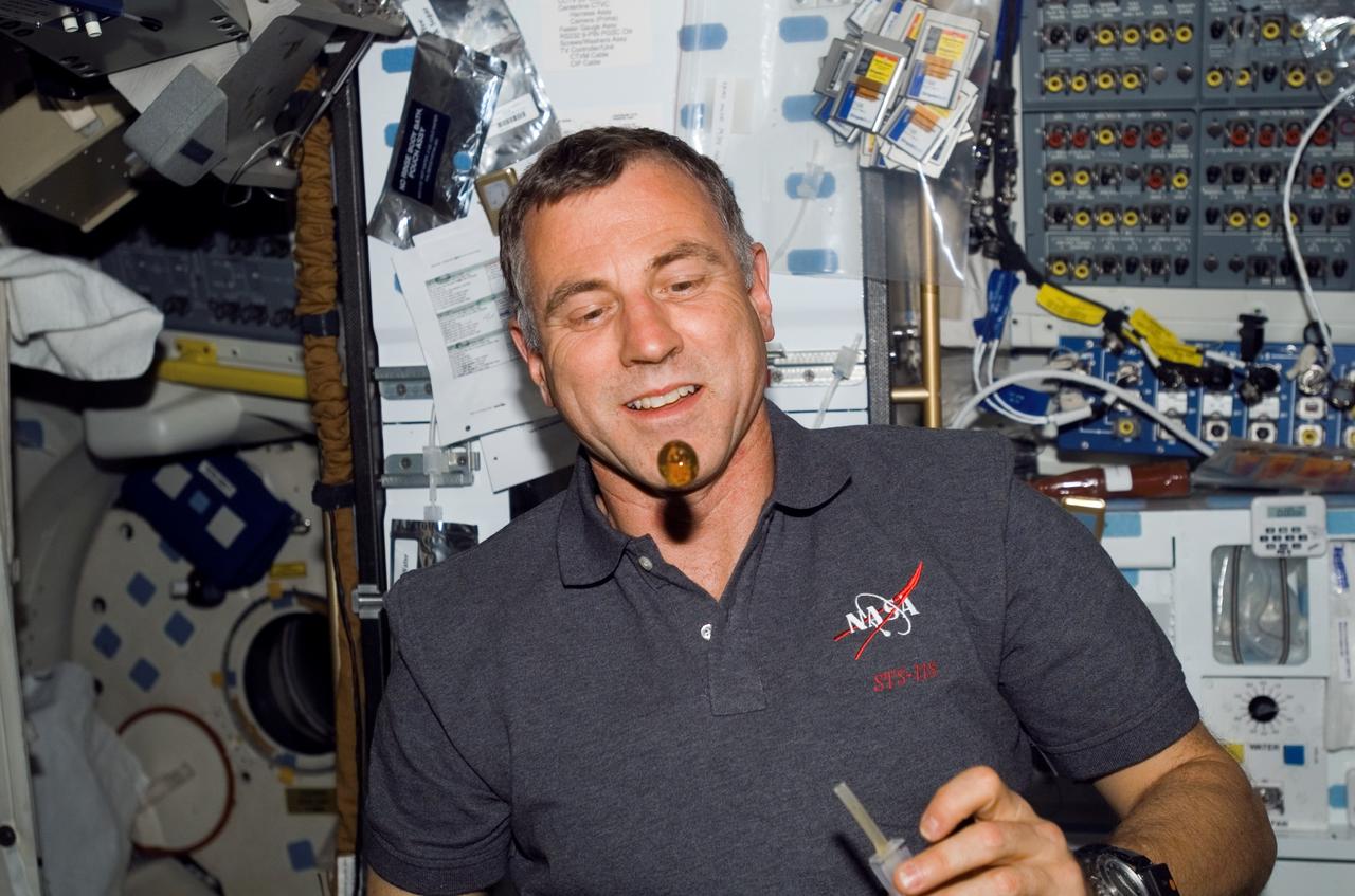 S118-E-07190 (14 Aug. 2007) --- Astronaut Dave Williams, STS-118 mission specialist representing the Canadian Space Agency, watches a bubble float freely, after having squeezed it from his beverage container, on the middeck of Space Shuttle Endeavour while docked with the International Space Station.