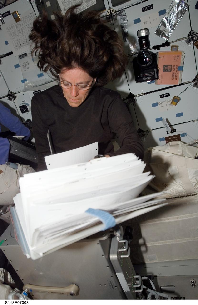 S118-E-07308 (15 Aug. 2007) --- Astronaut Barbara R. Morgan, STS-118 mission specialist, looks over procedures checklists on the middeck of Space Shuttle Endeavour while docked with the International Space Station.