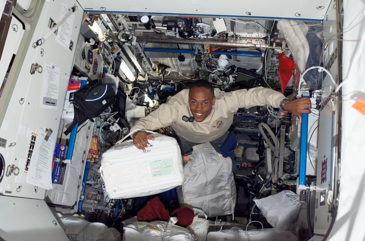 S118-E-07630 (16 Aug. 2007) --- Astronaut Alvin Drew, STS-118 mission specialist, moves a stowage container through the Destiny laboratory of the International Space Station while Space Shuttle Endeavour remains docked with the station.