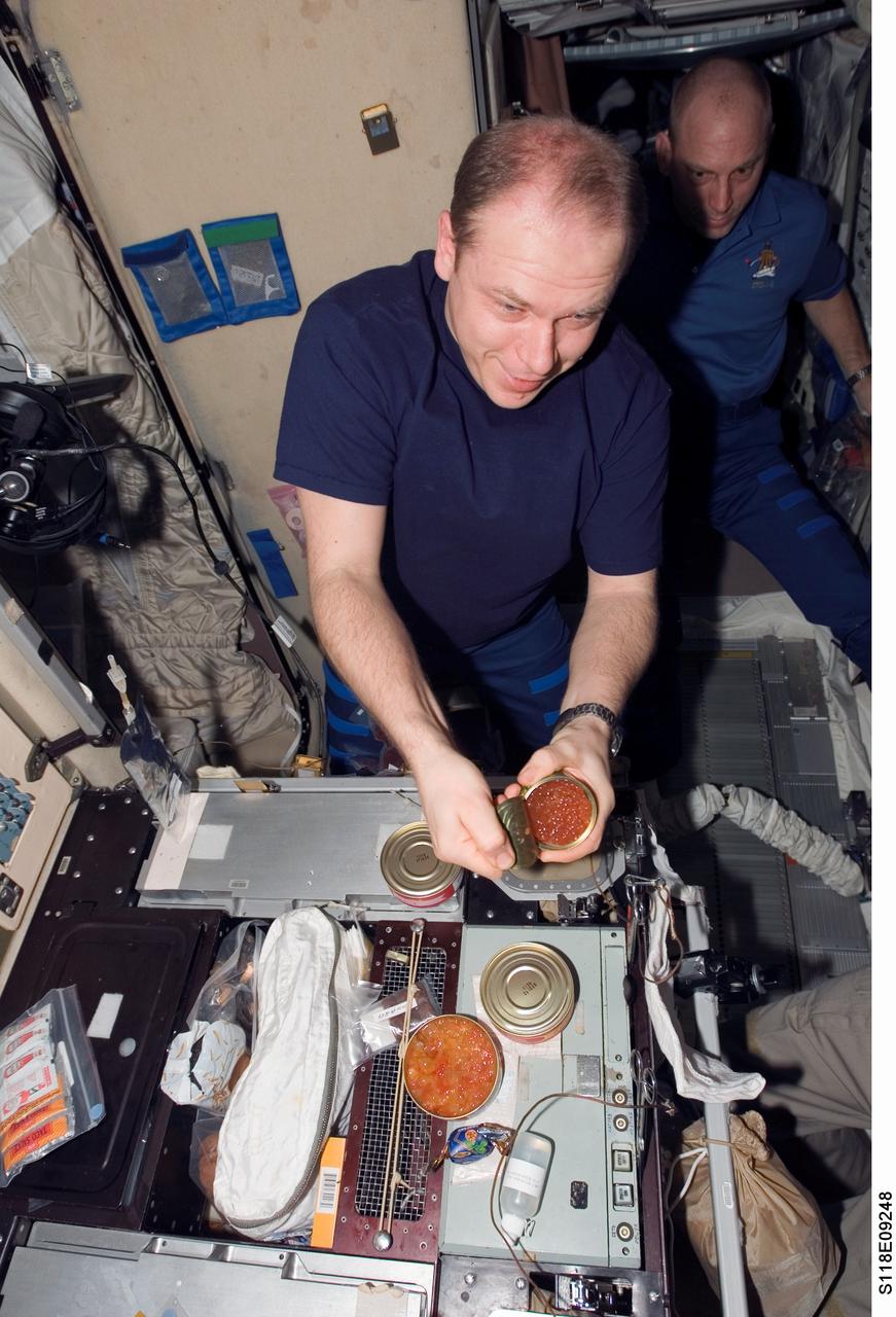 S118-E-09248 (18 Aug. 2007) --- Cosmonaut Oleg V. Kotov, Expedition 15 flight engineer representing Russia's Federal Space Agency, prepares to eat a meal at the galley during a farewell ceremony for the STS-118 crewmembers in the Zvezda Service Module of the International Space Station. Astronaut Clay Anderson, flight engineer, is visible in the background. Hatches were closed between the station and Space Shuttle Endeavour at 4:10 p.m. on Aug. 18.
