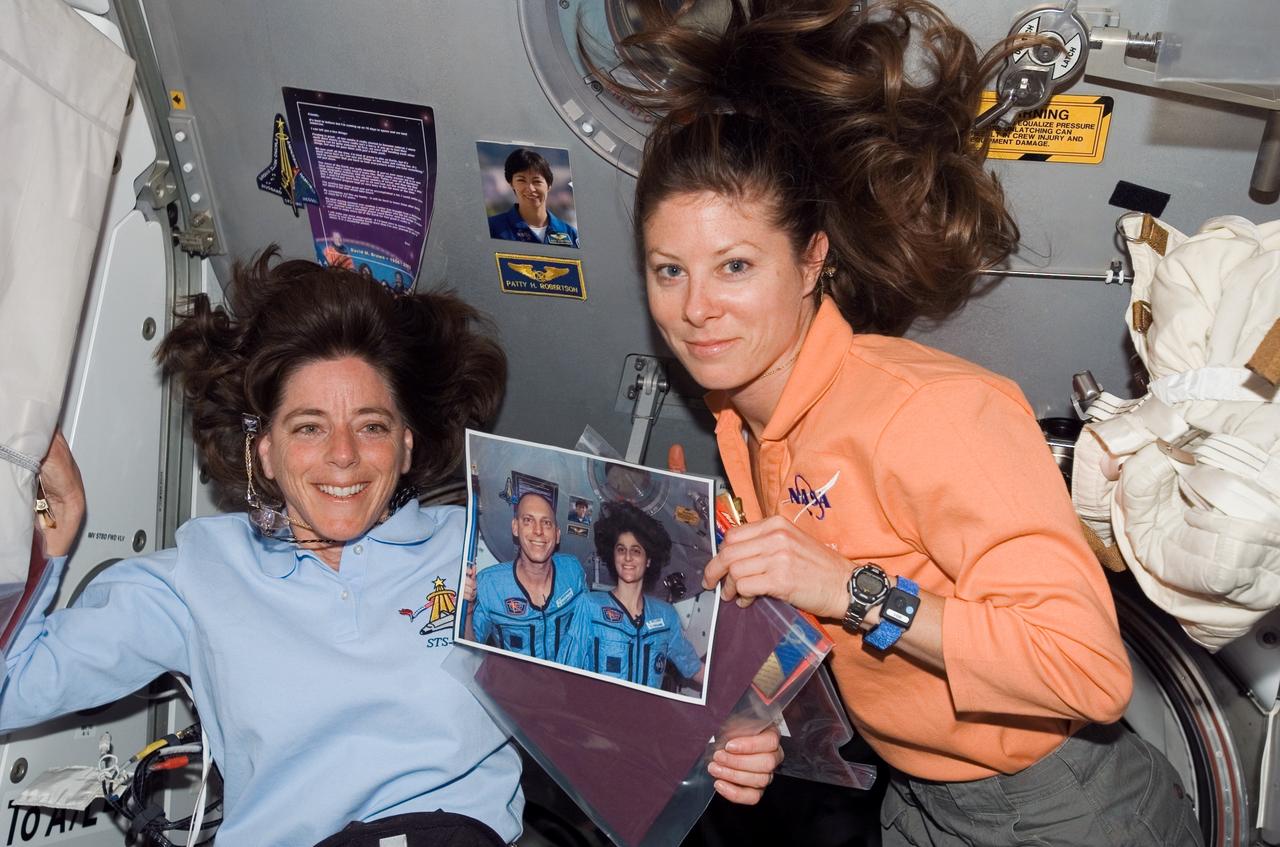 S118-E-09265 (18 Aug. 2007) --- Astronauts Barbara R. Morgan (left) and Tracy Caldwell, both STS-118 mission specialists, pose with a photo of astronauts Clay Anderson and Sunita Williams, both Expedition 15 flight engineers, near a hatch on the International Space Station while Space Shuttle Endeavour remains docked with the station.
