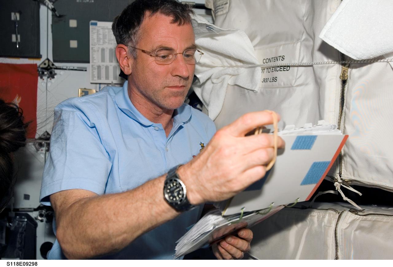 S118-E-09298 (18 Aug. 2007) --- Astronaut Dave Williams, STS-118 mission specialist representing the Canadian Space Agency, looks over procedures checklists on the middeck of Space Shuttle Endeavour as the crew makes preparations for their return home. Hatches were closed between the International Space Station and Endeavour at 4:10 p.m. on Aug. 18.