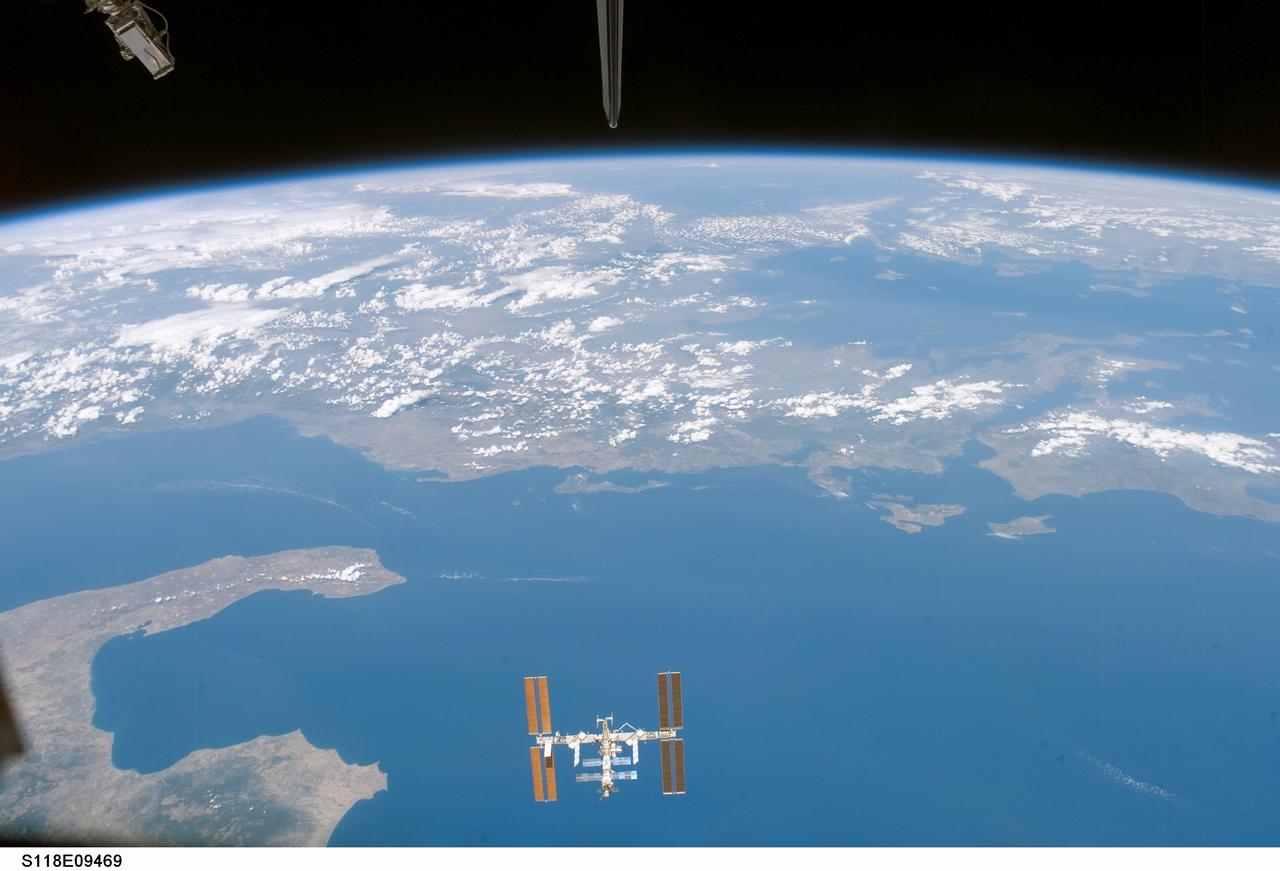 S118-E-09469 (19 Aug. 2007) --- The International Space Station is featured in this image photographed by a STS-118 crewmember on the Space Shuttle Endeavour following the undocking of the two spacecraft, which occurred at 6:56 a.m. (CDT) on Aug. 19, 2007. The image was acquired through one of the crew cabin windows, looking back over the length of the shuttle. Endeavour had undocked from the station, and the crew had begun late inspection of the orbiter's Thermal Protection System (wing leading edges, nosecap, and belly tiles) prior to landing. The late inspection is performed using sensors mounted on the Orbiter Boom Sensor System (OBSS) in order to assess whether micrometeorite or orbiting debris impacts had compromised the Thermal Protection System of the shuttle while it was docked with the station. This oblique image was acquired almost one hour after late inspection activities had begun. The sensor head of the OBSS is visible at top left. The entirety of the orbital outpost is visible at bottom center, set against the backdrop of the Ionian Sea approximately 330 kilometers below it. Other visible features of the southeastern Mediterranean region include the toe and heel features of Italy's "boot" at lower left, and the western coastlines of Albania and Greece extend across the center. Further towards the horizon, the Aegean and Black Seas are also visible.