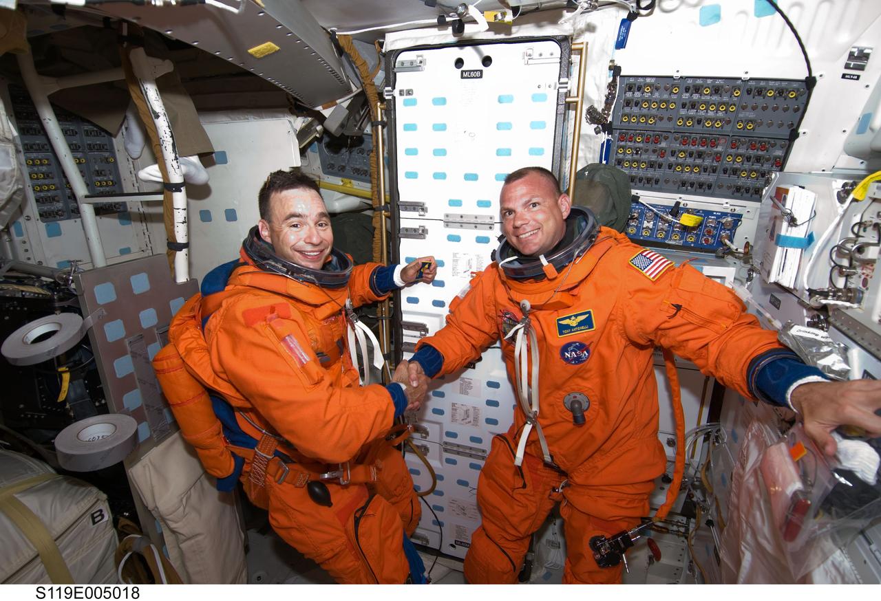 S119-E-005018 (15 March 2009) --- Attired in their shuttle launch and entry suits, astronauts Lee Archambault (left), STS-119 commander; and Tony Antonelli, pilot, shake hands on the middeck of Space Shuttle Discovery during postlaunch activities.