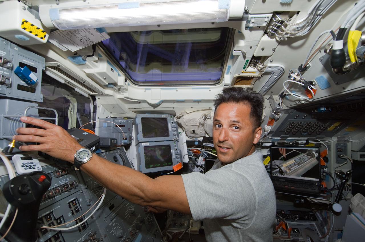 S119-E-005027 (15 March 2009) --- Astronaut Joseph Acaba, STS-119 mission specialist, works the controls of Space Shuttle Discovery’s remote manipulator system (RMS) robotic arm on the aft flight deck during flight day one activities.
