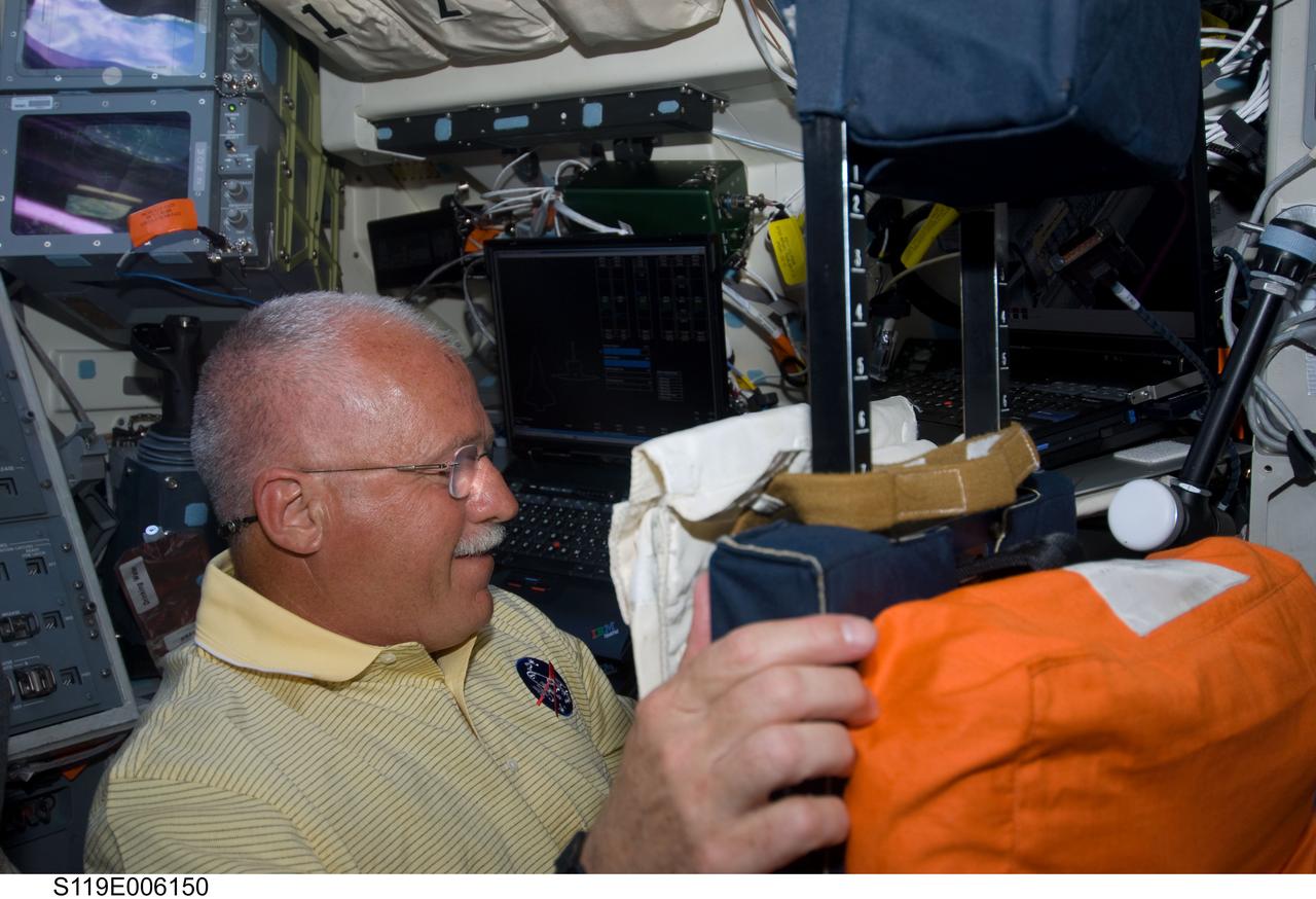S119-E-006150 (16 March 2009) --- Astronaut John Phillips, STS-119 mission specialist, works on the flight deck of Space Shuttle Discovery during flight day two activities.