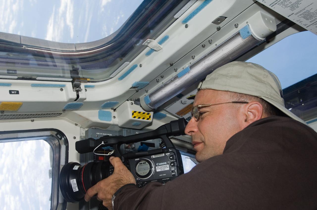 S119-E-006155 (16 March 2009) --- Astronaut Lee Archambault, STS-119 commander, uses a HD video camera at a window on the aft flight deck of Space Shuttle Discovery during flight day two activities.