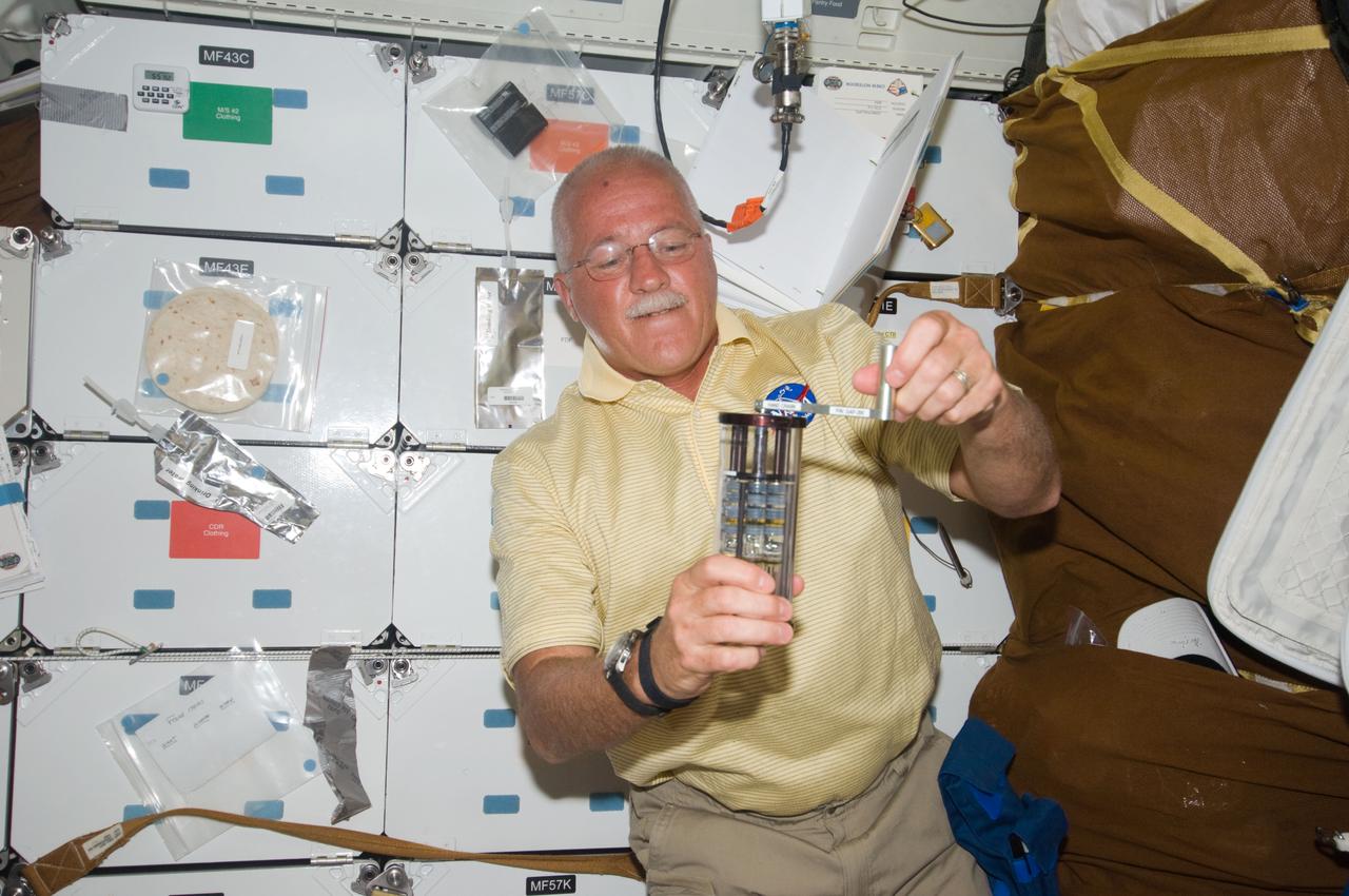 S119-E-006156 (16 March 2009) --- Astronaut John Phillips, STS-119 mission specialist, works with Group Activation Packs (GAP) on the middeck of Space Shuttle Discovery during flight day two activities.