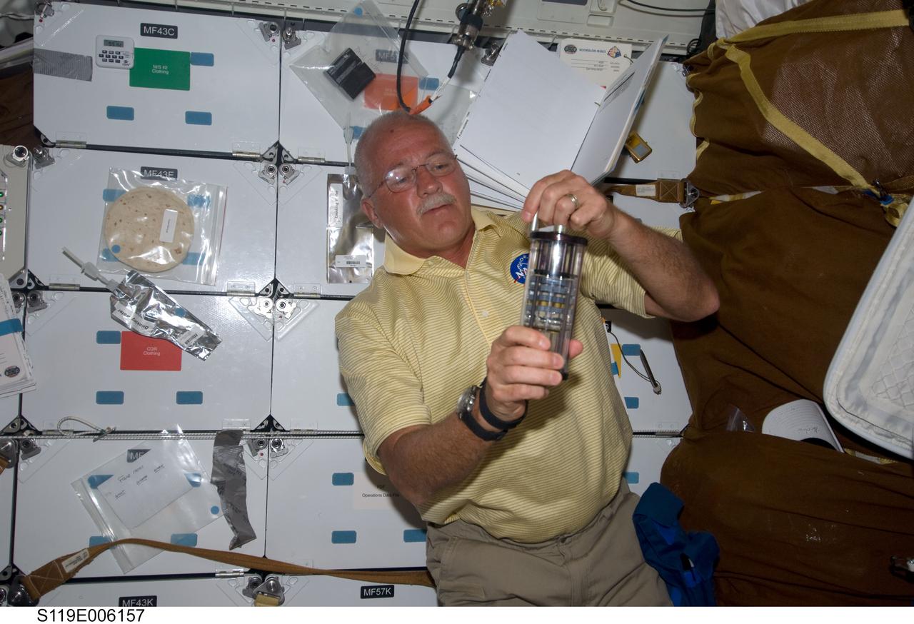 S119-E-006157 (16 March 2009) --- Astronaut John Phillips, STS-119 mission specialist, works with Group Activation Packs (GAP) on the middeck of Space Shuttle Discovery during flight day two activities.
