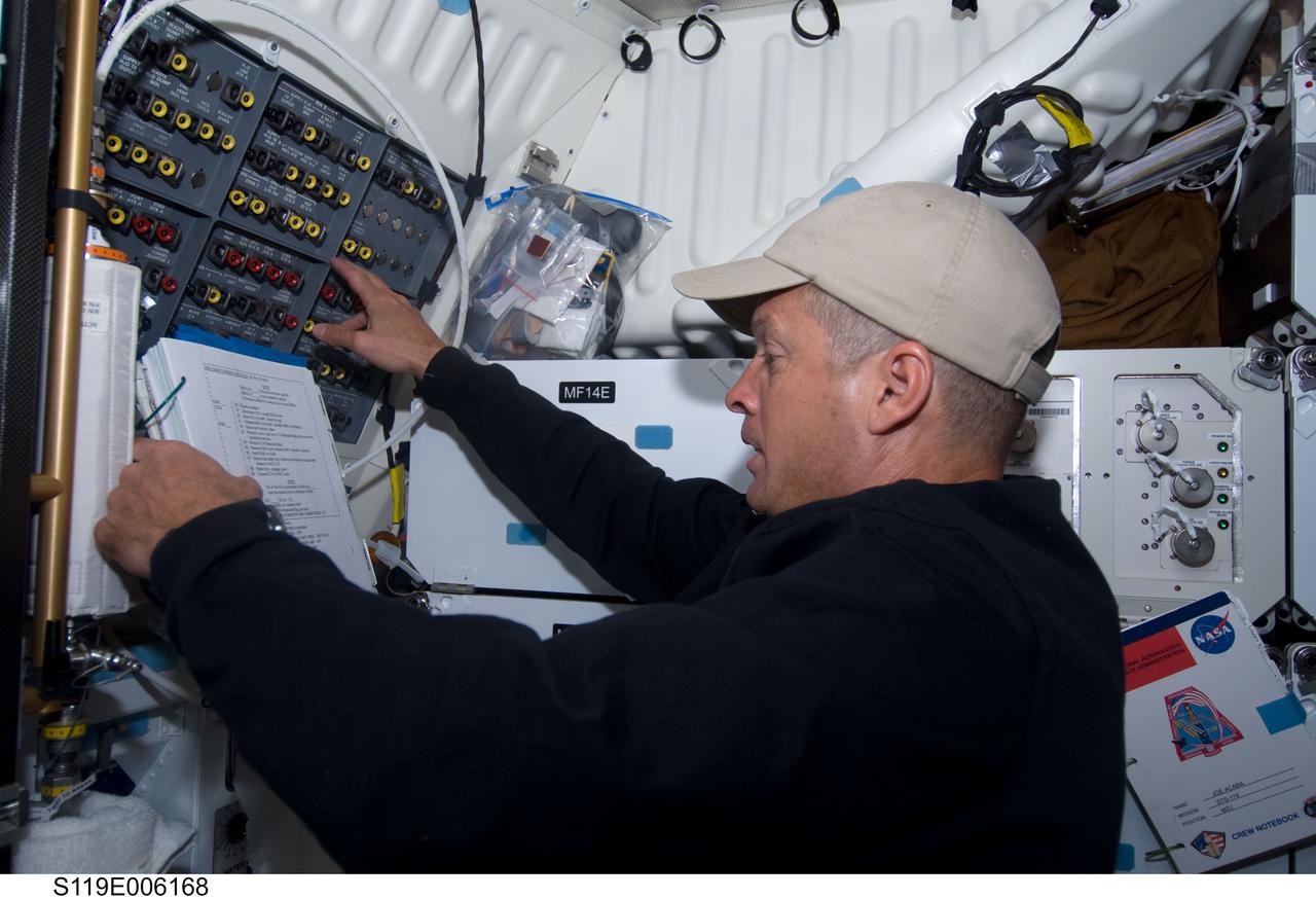 S119-E-006168 (16 March 2009) --- Astronaut Steve Swanson, STS-119 mission specialist, reads a procedures checklist while working on the middeck of Space Shuttle Discovery during flight day two activities.