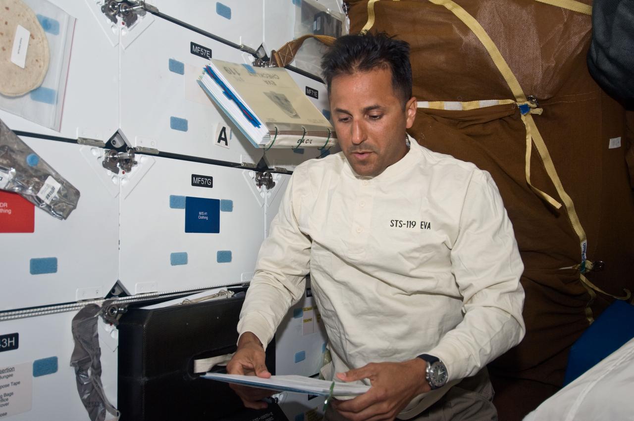 S119-E-006184 (16 March 2009) --- Astronaut Joseph Acaba, STS-119 mission specialist, looks over a procedures checklist on the middeck of Space Shuttle Discovery during flight day two activities.