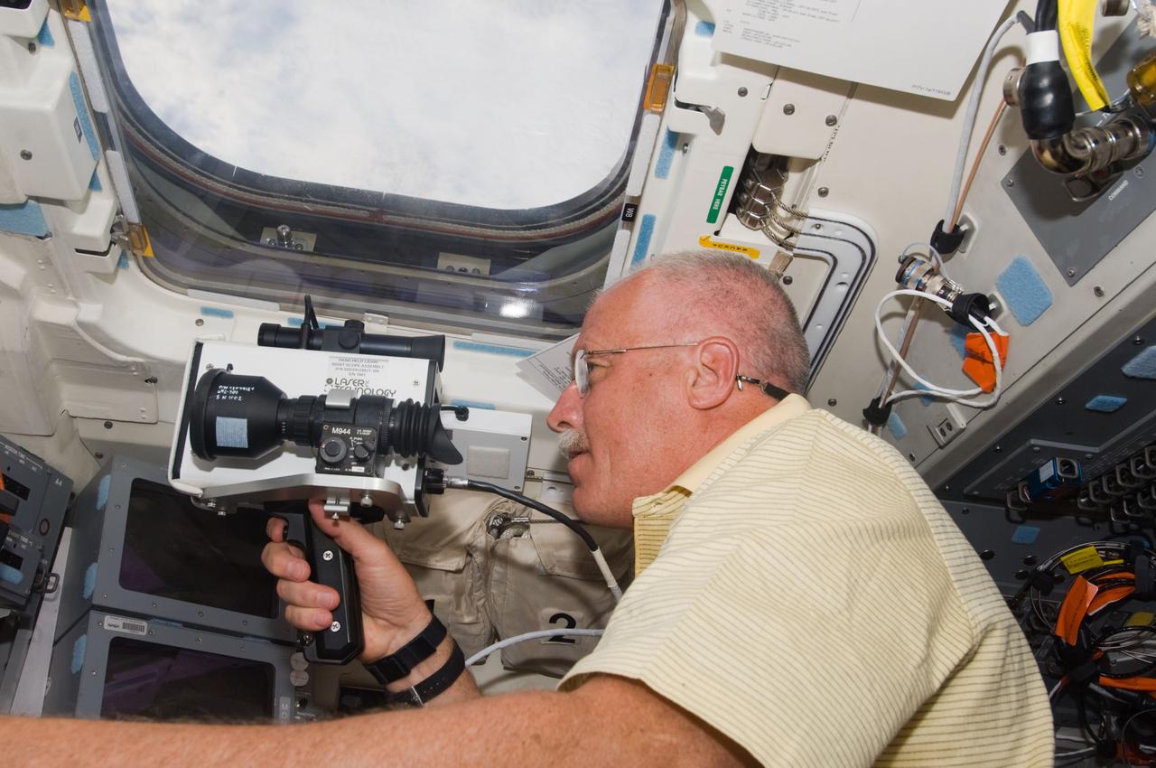 S119-E-006194 (16 March 2009) --- Astronaut John Phillips, STS-119 mission specialist, uses a handheld laser ranging device -- designed to measure the range between two spacecraft -- through one of the windows on the aft flight deck of Space Shuttle Discovery during flight day two activities.