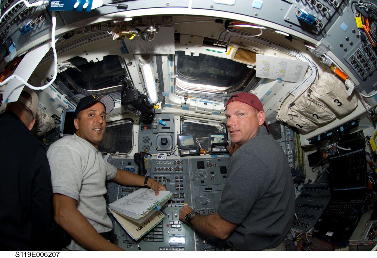 S119-E-006207 (16 March 2009) --- Astronauts Tony Antonelli (right), STS-119 pilot, and Joseph Acaba, mission specialist, take a moment for a photo as they work controls on the aft flight deck of Space Shuttle Discovery during flight day two activities.