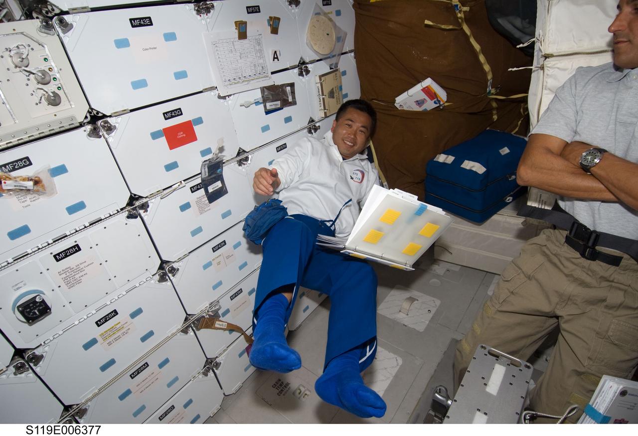 S119-E-006377 (17 March 2009) --- Japan Aerospace Exploration Agency (JAXA) astronaut Koichi Wakata, STS-119 mission specialist, works on the middeck of Space Shuttle Discovery during flight day three activities. Astronaut Joseph Acaba (partially out of frame), mission specialist, is at right.