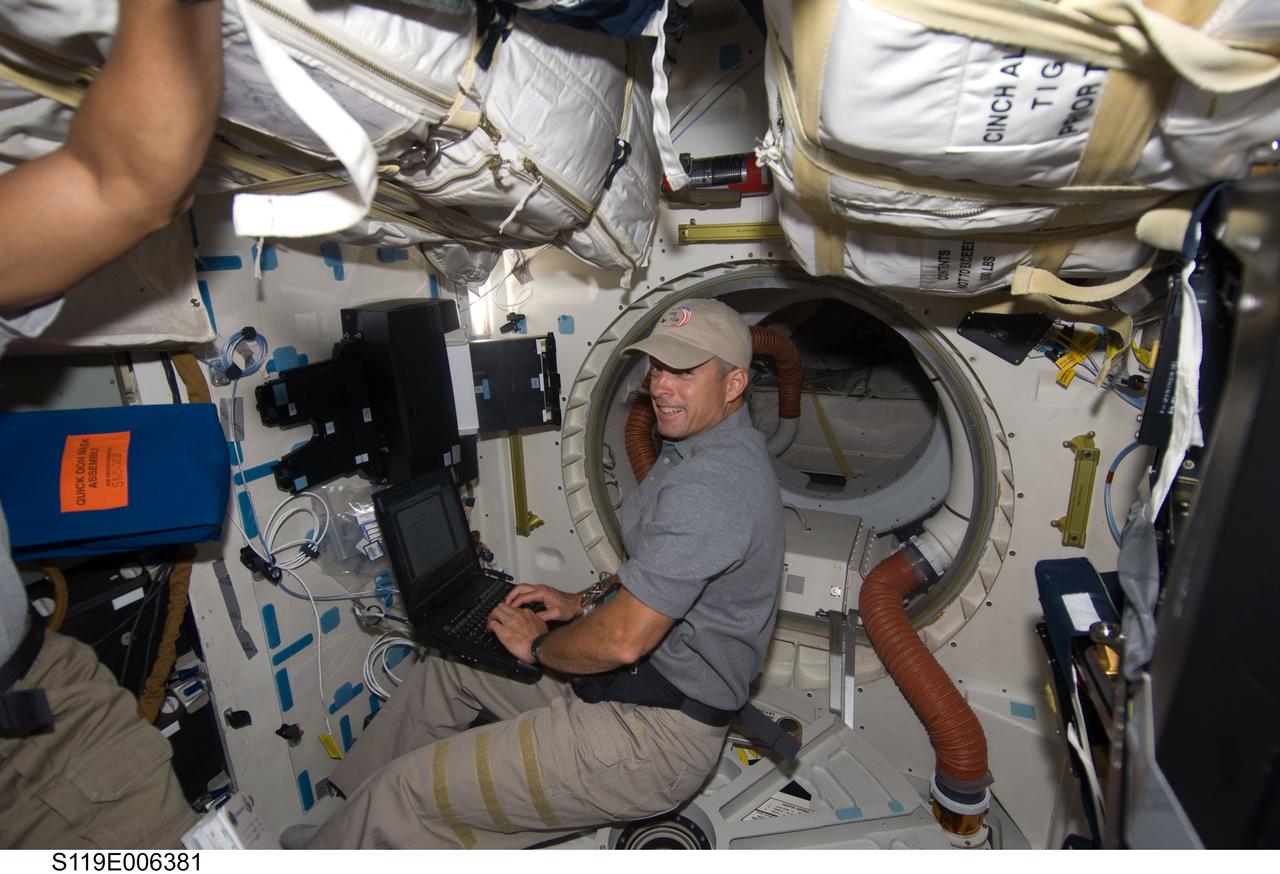 S119-E-006381 (17 March 2009) --- Astronaut Steve Swanson, STS-119 mission specialist, uses a computer on the middeck of Space Shuttle Discovery during flight day three activities.