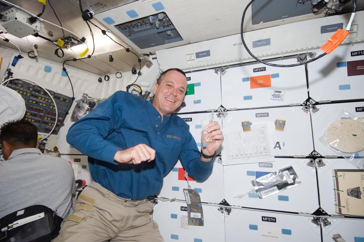 S119-E-006385 (17 March 2009) --- Astronaut Richard Arnold, STS-119 mission specialist, prepares to eat a snack near the galley on the middeck of Space Shuttle Discovery.