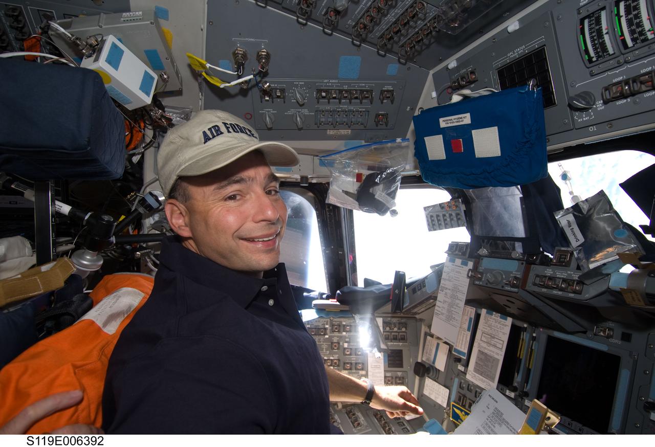 S119-E-006392 (17 March 2009) --- Astronaut Lee Archambault, STS-119 commander, smiles for a photo while monitoring data at the commander's station on the flight deck of Space Shuttle Discovery during flight day three activities.