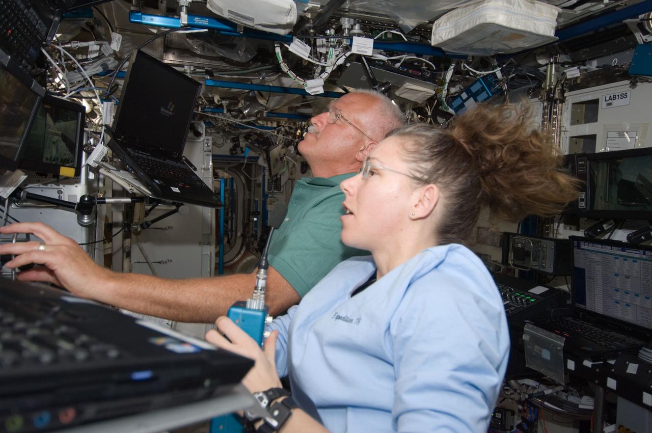 S119-E-006554 (18 March 2009) --- Astronauts John Phillips (background) and Sandra Magnus, both STS-119 mission specialists, work the controls of the station's robotic Canadarm2 in the Destiny laboratory of the International Space Station while Space Shuttle Discovery is docked with the station.