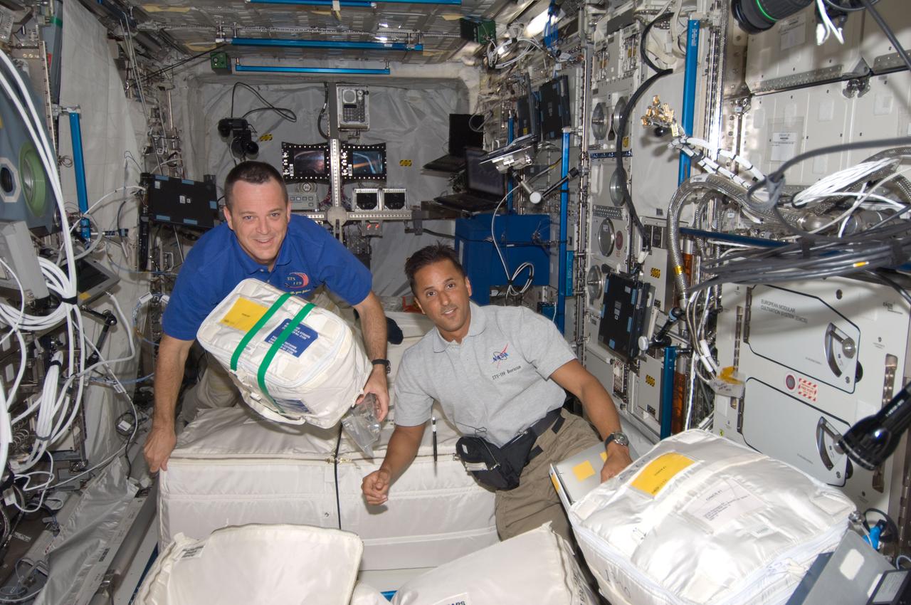 S119-E-006563 (18 March 2009) --- Astronauts Richard Arnold (left) and Joseph Acaba, both STS-119 mission specialists, work with stowage containers in the Columbus laboratory of the International Space Station while Space Shuttle Discovery is docked with the station.